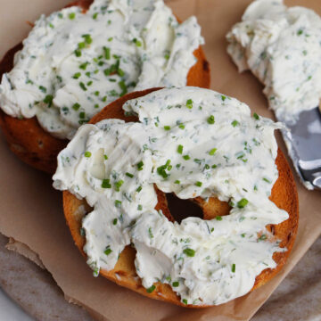 bagel with herb cream cheese next to knife.