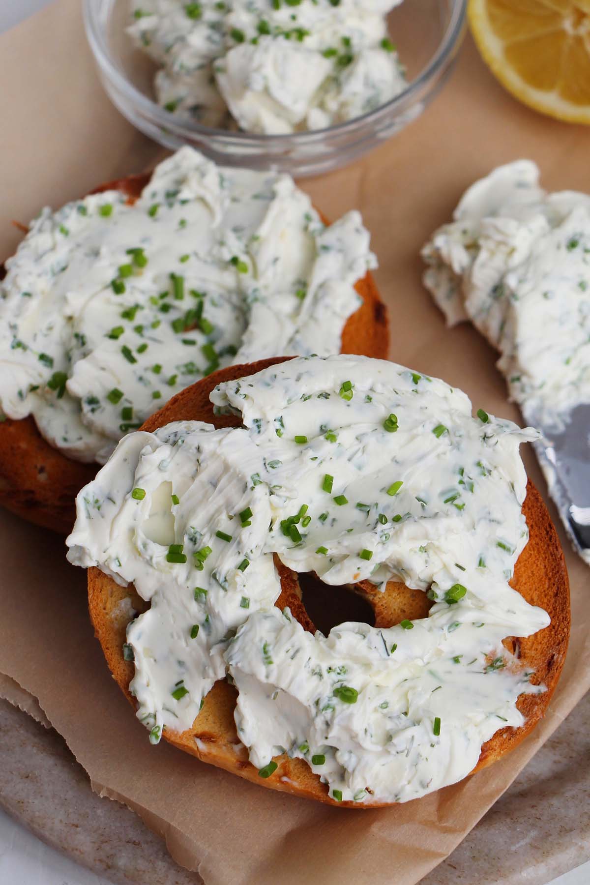 bagel with herb cream cheese next to knife.