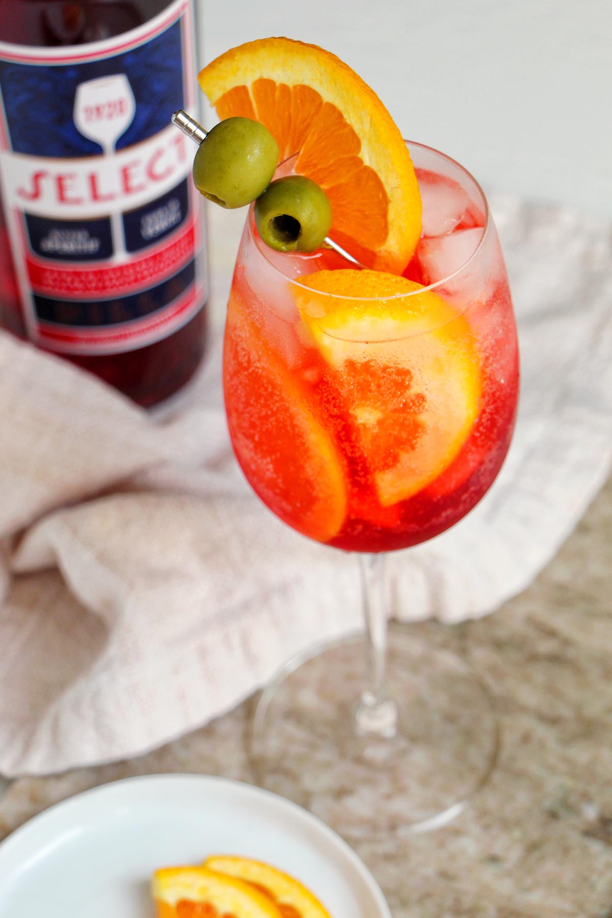 Select spritz in wine glass next to liquor bottle.