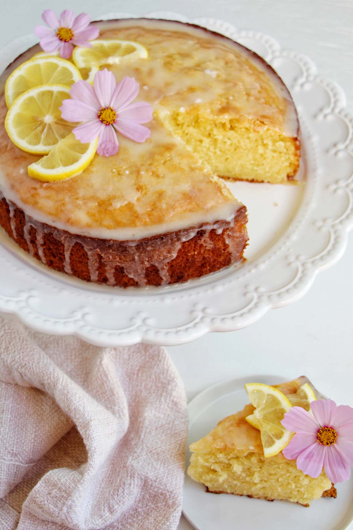 lemon olive oil cake on a stand next to slice of cake.