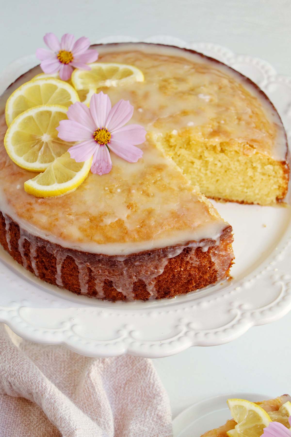 lemon olive oil cake topped with glaze, lemons, and edible flowers.