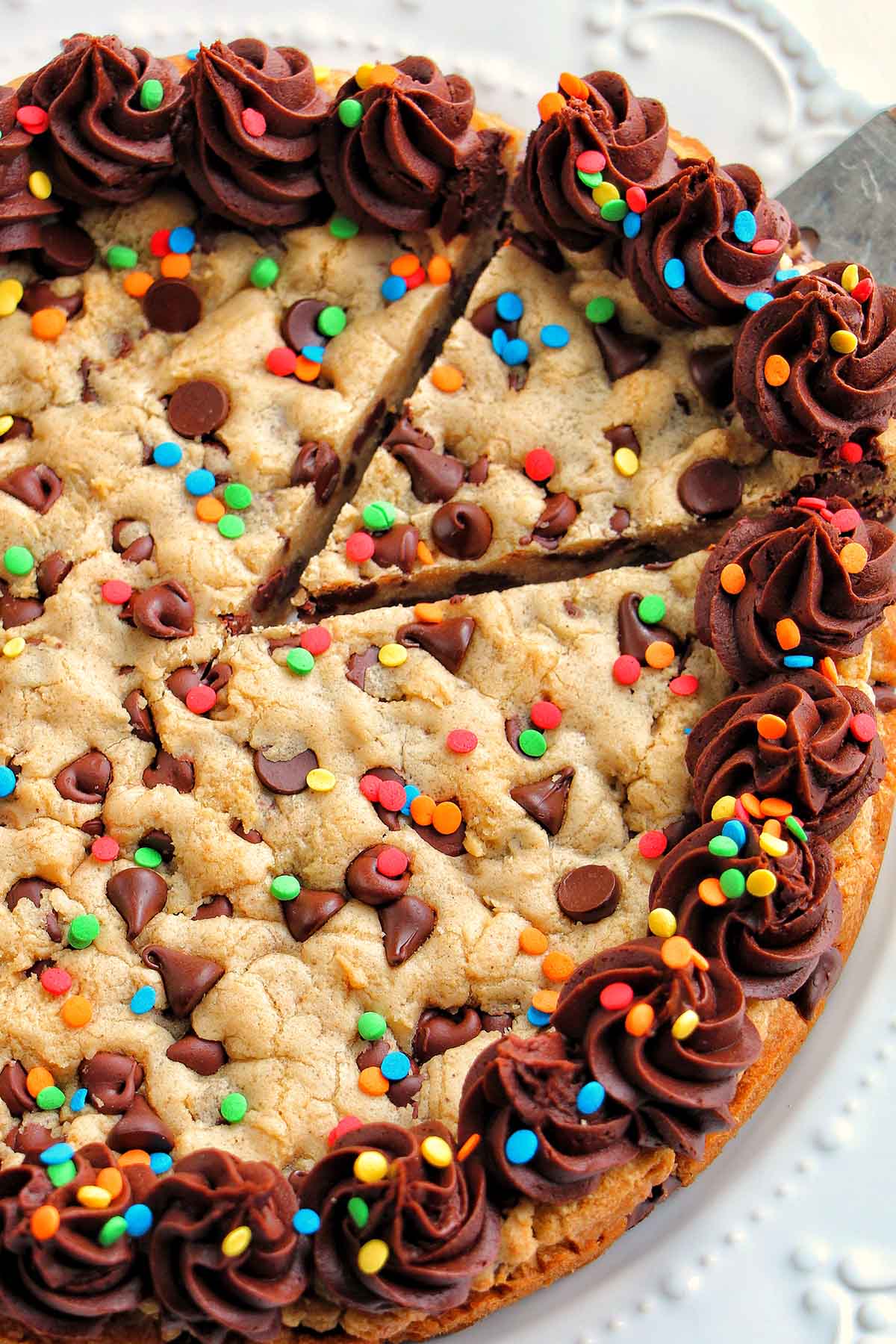 taking a slice of cookie cake with chocolate frosting.