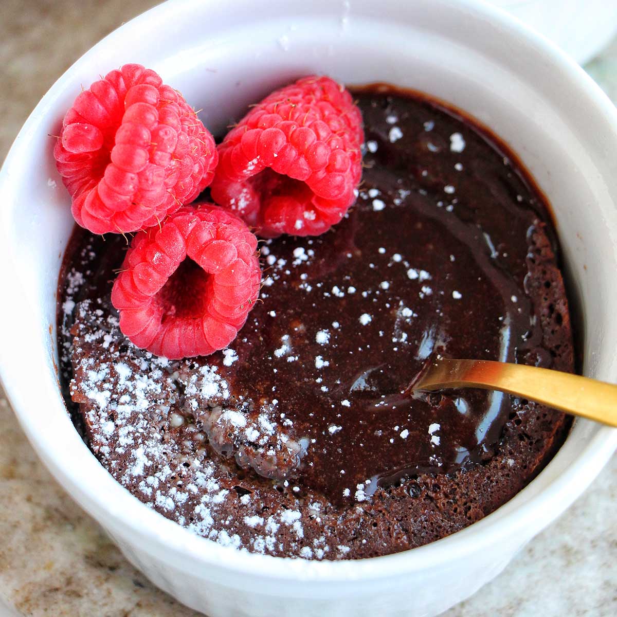 molted lava cake in a ramekin with raspberries.