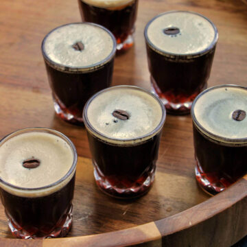 espresso martini shots on a wooden tray.