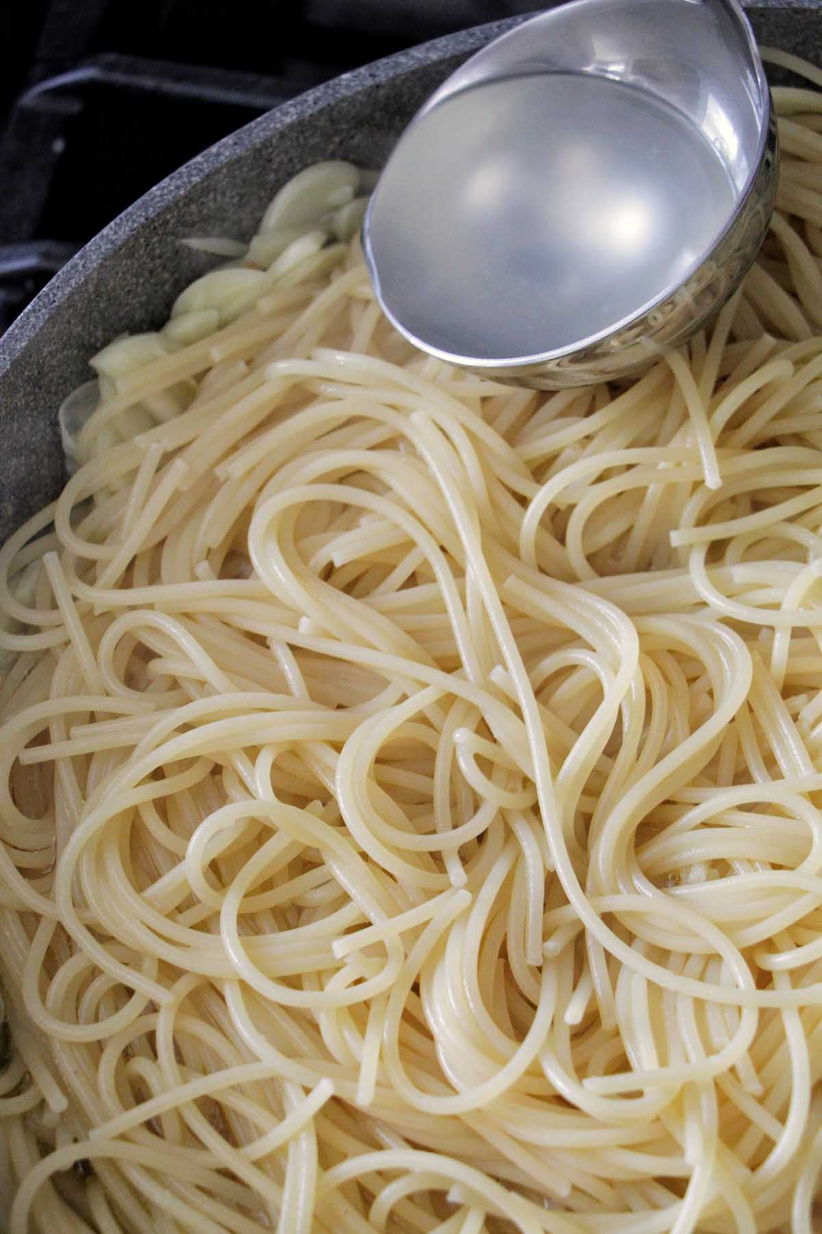 pouring pasta water on spaghetti.