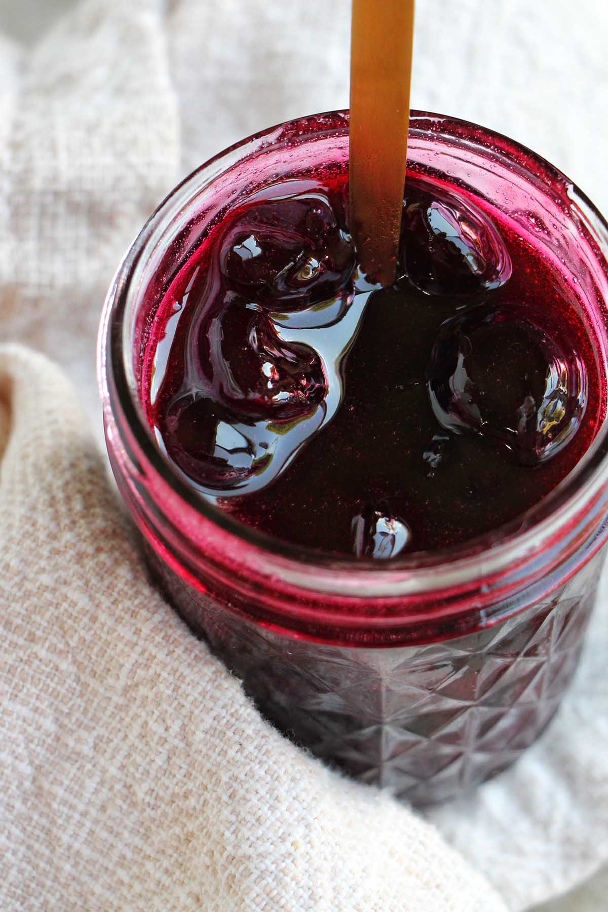 cherry jam in a jar with a spoon.