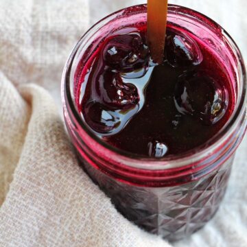 cherry jam in a jar with a spoon.