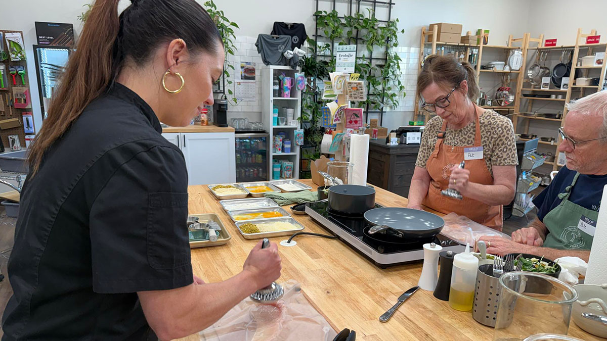 two people cooking next to a culinary instructor.