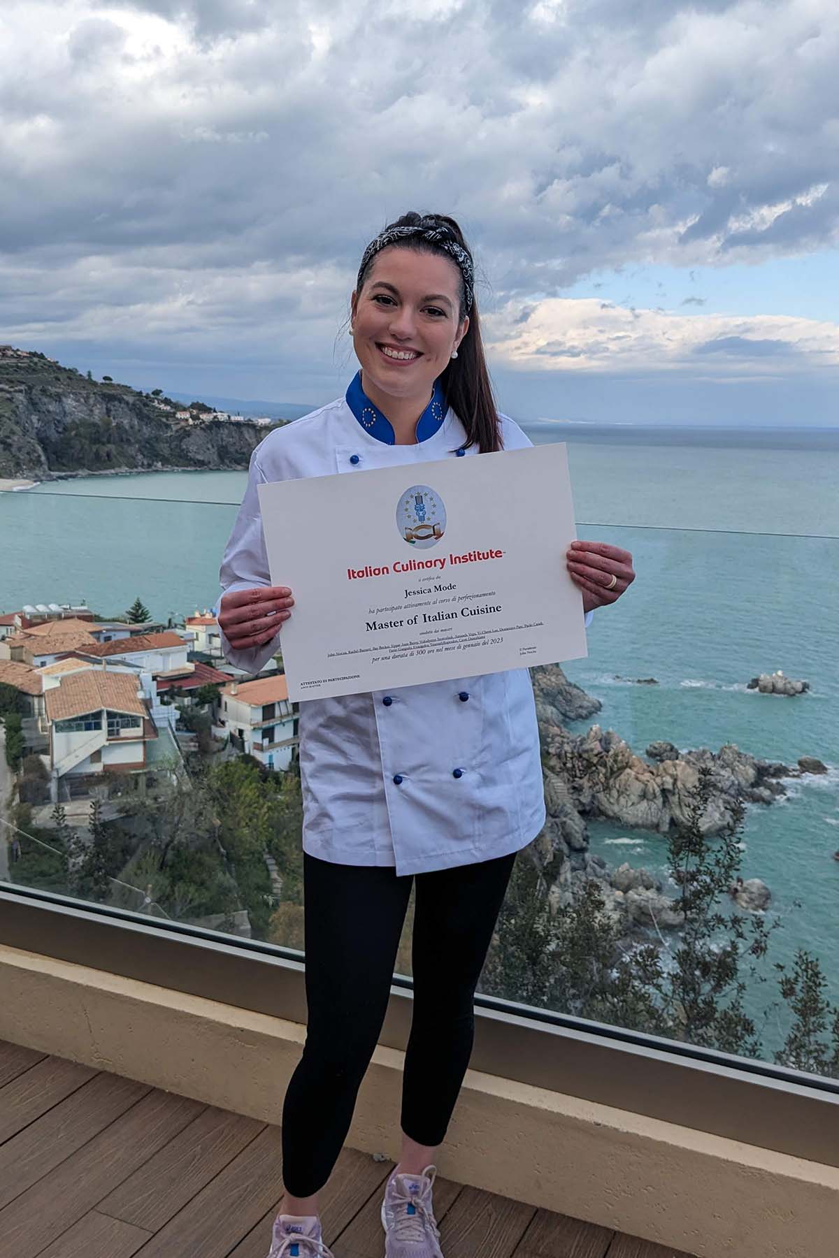 girl holding a certificate in front of sea view.