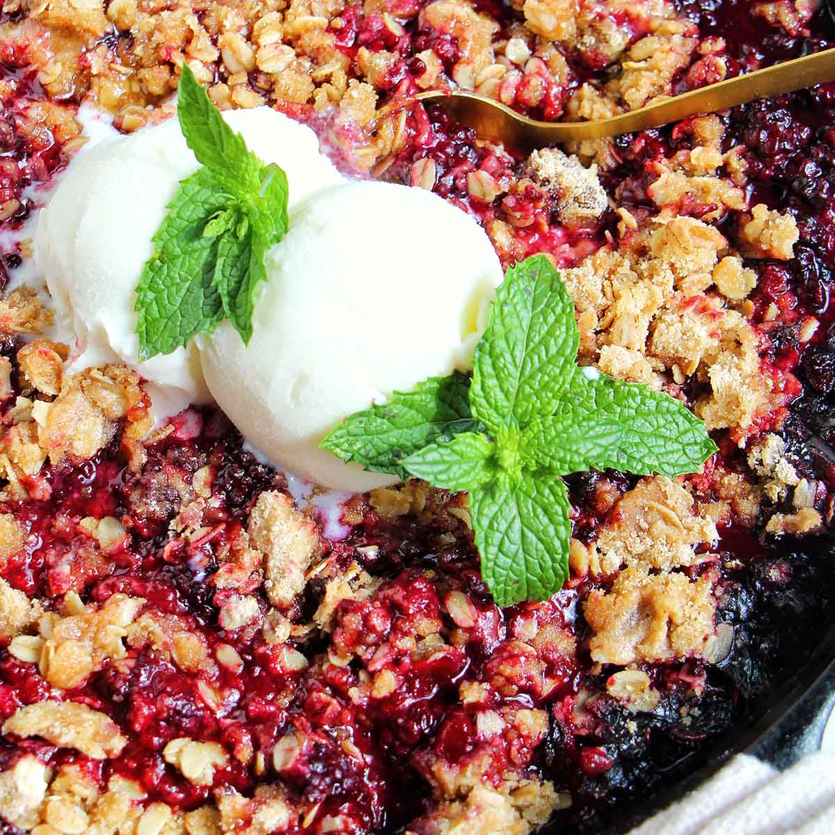 blackberry crisp in a cast iron skillet with ice cream.
