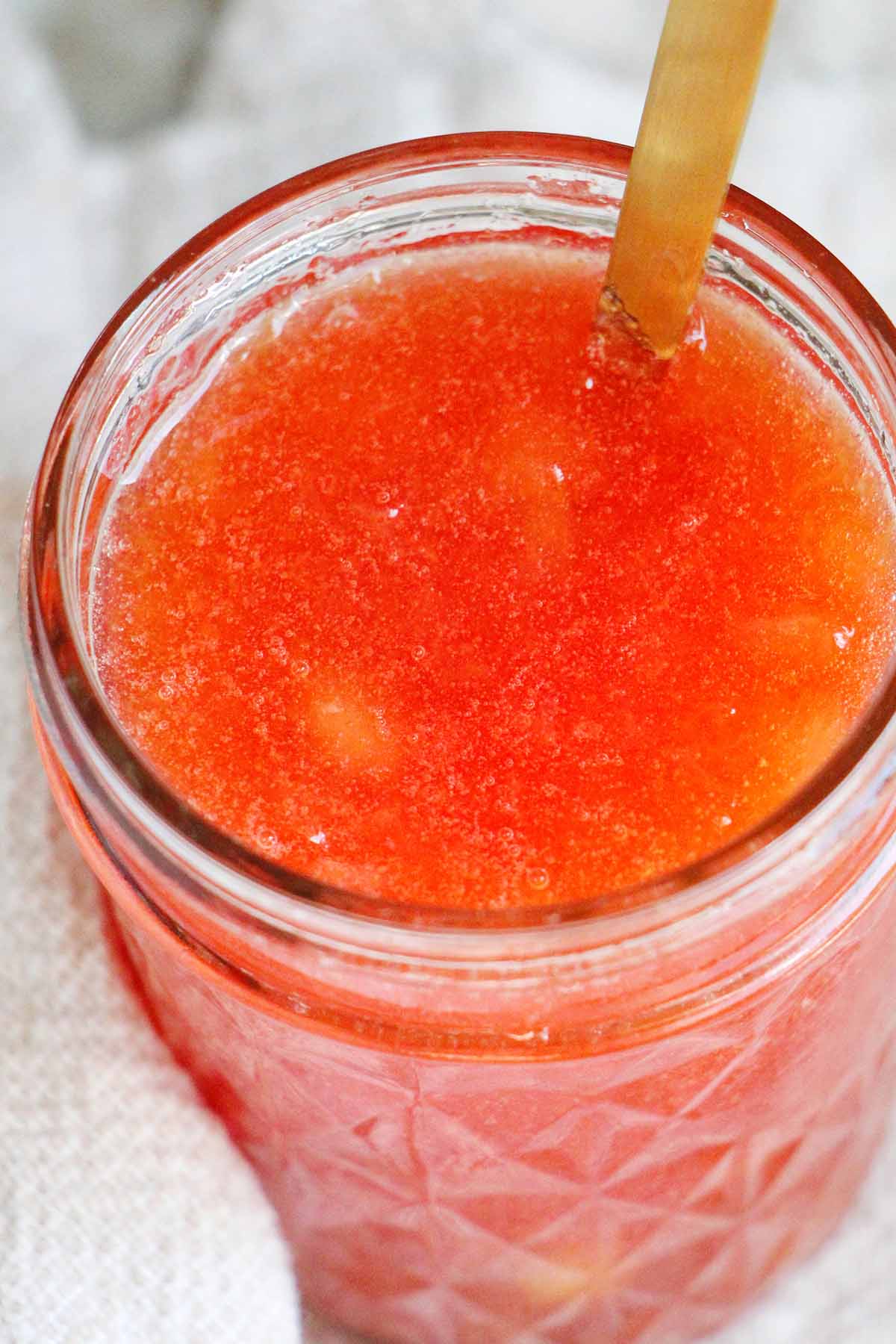 plum jam in mason jar with gold spoon.