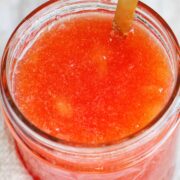 plum jam in mason jar with gold spoon.