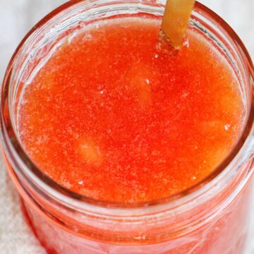 plum jam in mason jar with gold spoon.